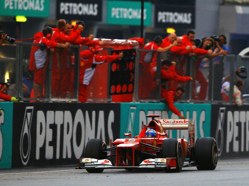 The Ferrari team line the pitwall as Alonso crosses the finish line