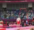 The gymnasts compete in front of rows of empty seats