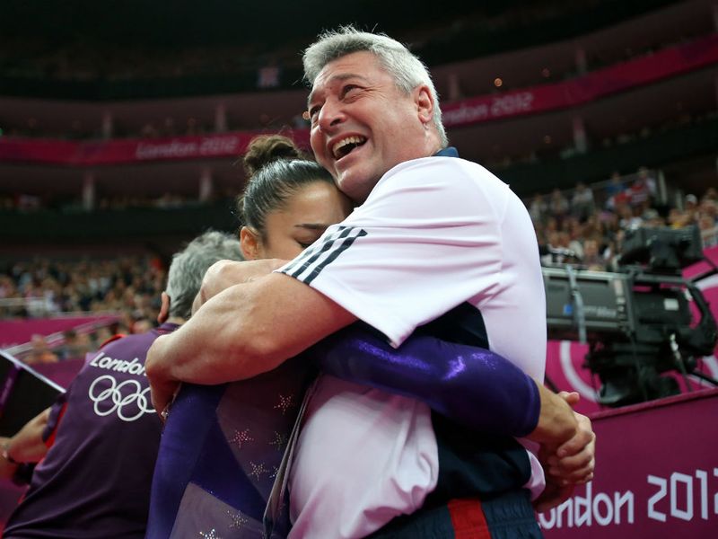 Raisman is embraced by her coach as the Ameican team qualify first with a points total of 181.863
