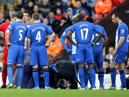 Wigan's players surround the injured Ben Watson