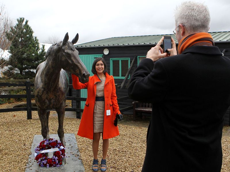 A racegoer poses with Cheltenham's Best Mate statue