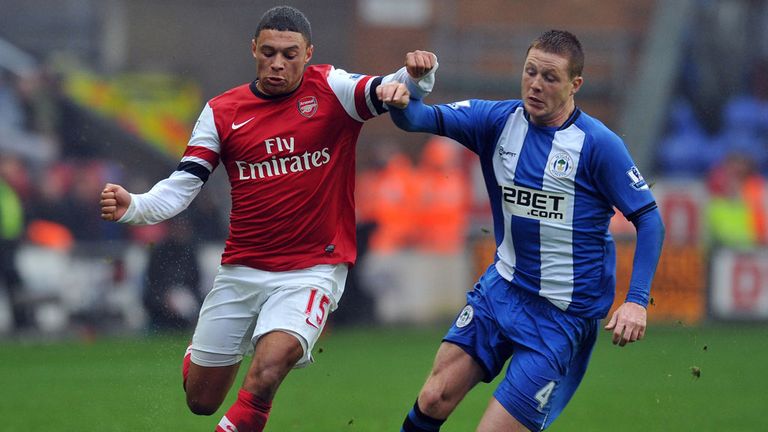 Alex Oxlade-Chamberlain (left) holds off Wigan's James McCarthy