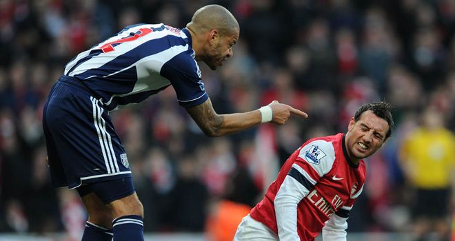 Santi Cazorla winces in pain despite Steven Reid's attempted challenge missing his leg