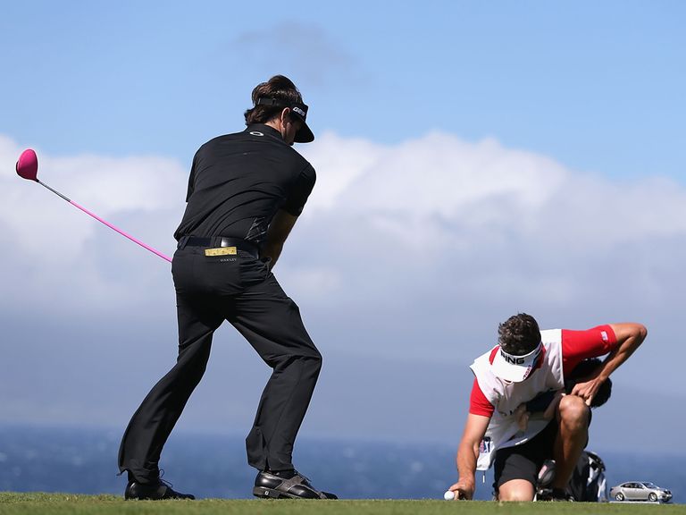 Bubba Watson pretends to tee off while his caddie holds the ball still