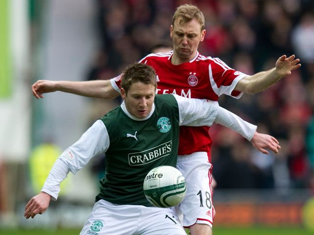 Paul Cairney is kept in check by Stephen Hughes.