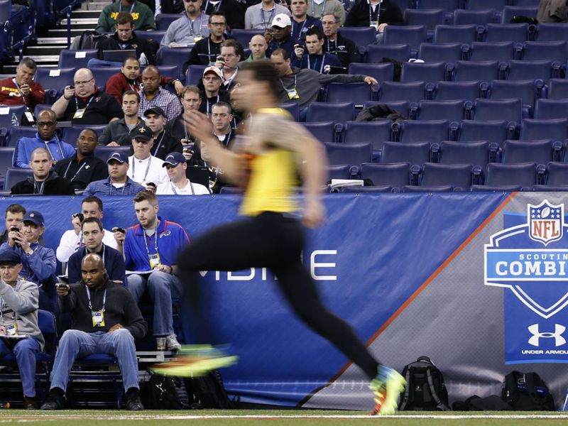 Scouts watch on at t he NFL Combine as another hopeful flies by