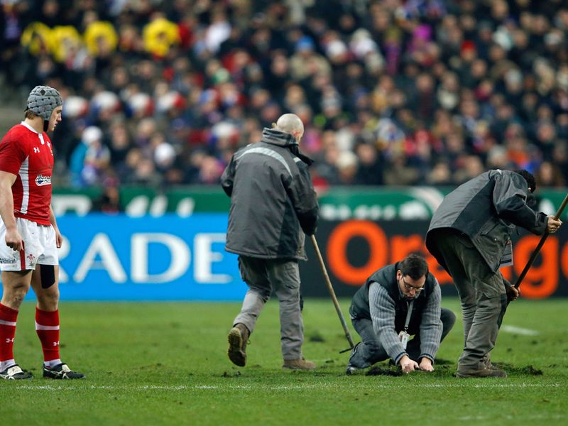 Running repairs: Groundsmen come on to sort out the pitch as it cuts up badly