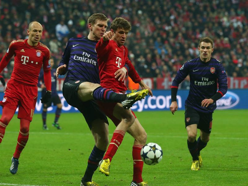Arsenal defender Per Mertesacker tries to clear the ball away from Bayern Munich's Thomas Muller