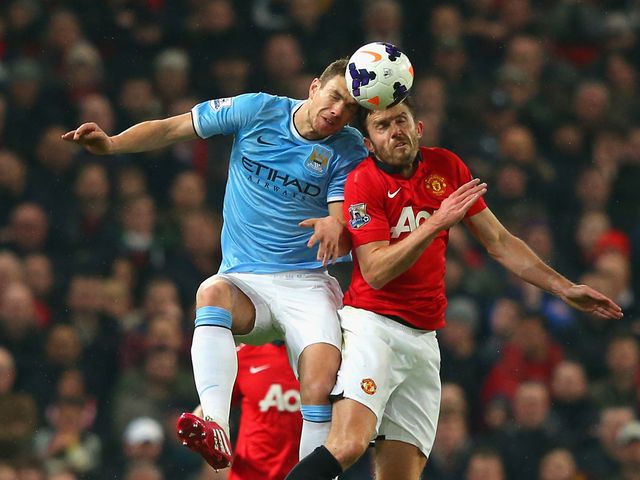 Michael Carrick and Edin Dzeko challenge for a header