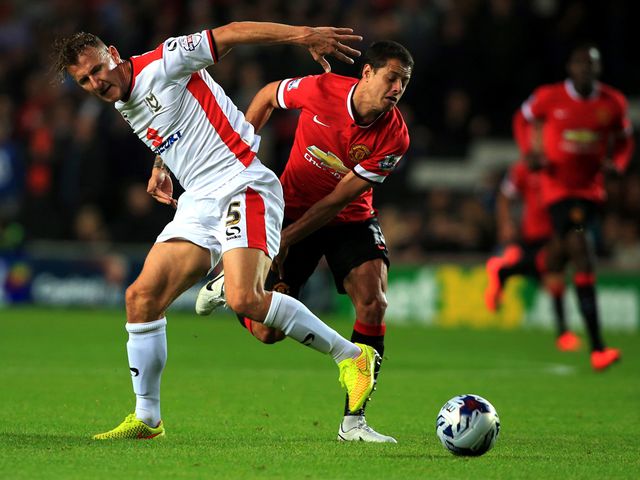 MK Dons' Antony Kay tussles with Manchester United's Javier Hernandez