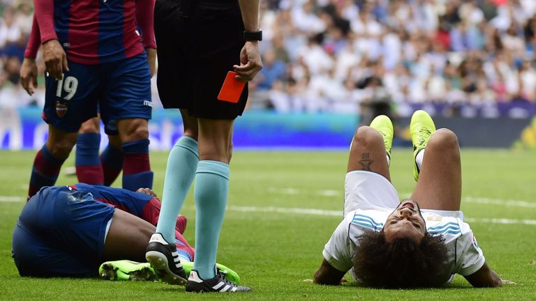 The referee waits with his red card as Marcelo lies on the ground after colliding with, and then kicking, Jefferson Lerma