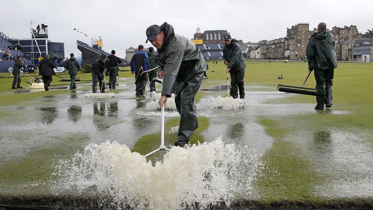 Greenkeepers sweep water into the Swilcan Burn from the first fairway at St Andrews 