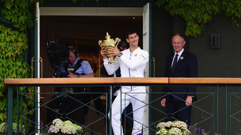 Novak Djokovic celebrates with the trophy on the clubhouse balcony