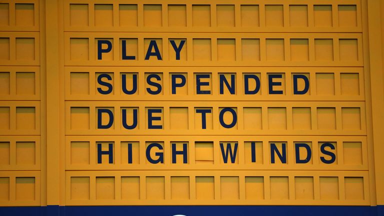 A scoreboard displays that play is suspended due to high winds