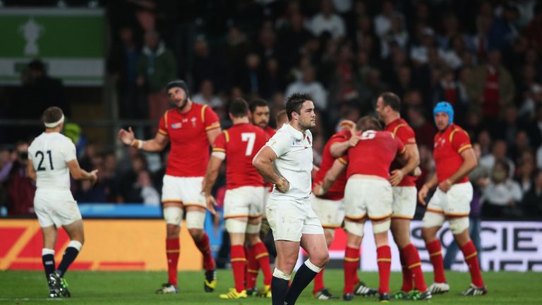 Brad Barritt of England looks dejected as the Wales team celebrates victory