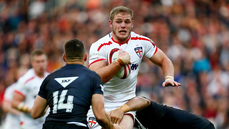 Tom Burgess of England is tackled by Lewis Brown and Ben Matulino of New Zealand 