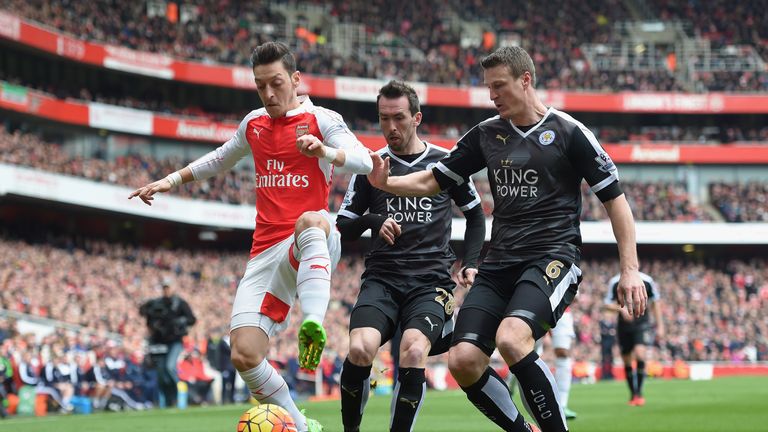 Mesut Ozil (left) holds off the attentions of Robert Huth