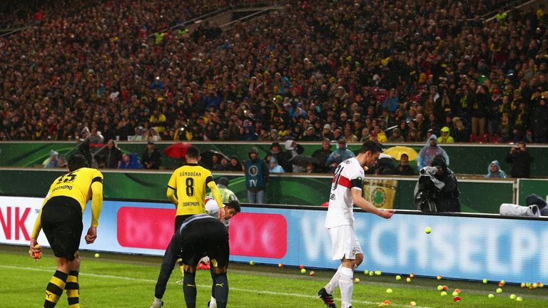 Both sets of players clear tennis balls from the pitch at the Mercedes-Benz Arena