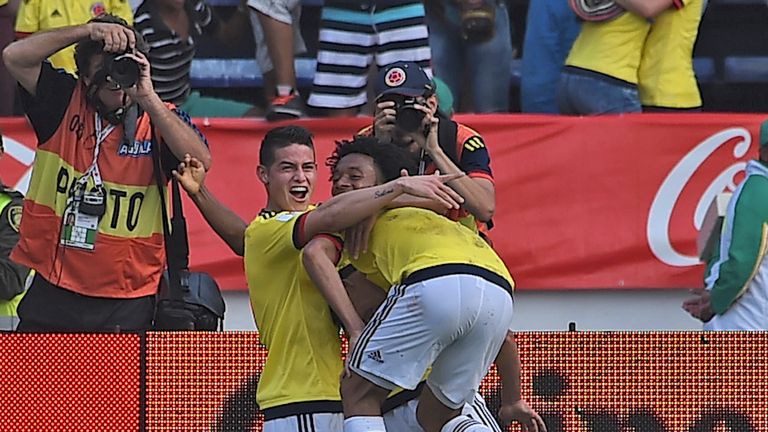 Colombia's Carlos Bacca (back to camera) celebrates with teammates James Rodriguez (L) and Juan Cuadrado after scoring against Ecuador