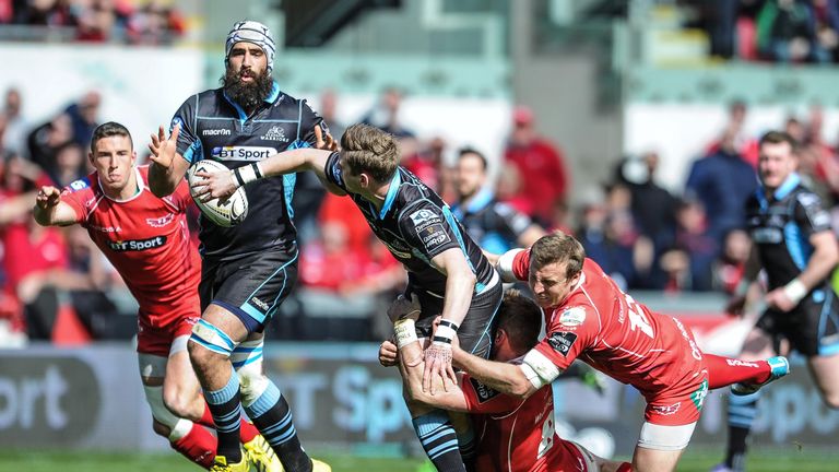 Finn Russell offloads despite the tackle of Scarlets' Hadleigh Parkes