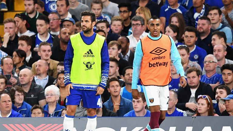 Fabregas warms up on the sidelines alongside West Ham midfielder Dimitri Payet