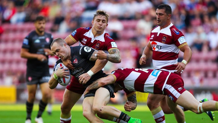 St Helens' Adam Swift is tackled by Wigan's Sam Powell and John Bateman