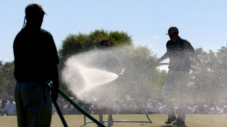 Ground staff water the greens between groups on the final day in 2004