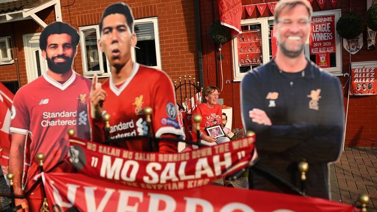 Liverpool fan Emily Farley waits for the result of Chelsea vs Man City outside her home in Liverpool, decorated with banners and cut-outs