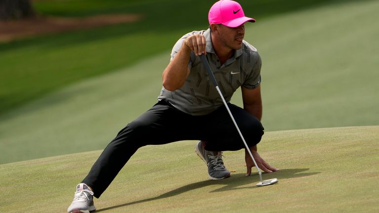 Brooks Koepka stretches to line up a putt on the 14th green, adopting his 'Power Ranger' pose