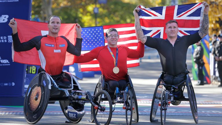 Second place finisher Marcel Hug of Switzerland (left), winner Daniel Romanchuk of the United States (centre) and third place finisher David Weir at the finish line of the New York City marathon