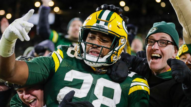 AJ Dillon celebra con los fanáticos locales de Green Bay mientras hace un 'Lambeau Leap' en la multitud después de uno de sus dos touchdowns.