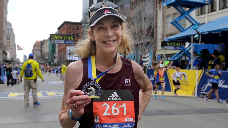 Switzer wears the same bib number and displays her medal after finishing the Boston Marathon in 2017