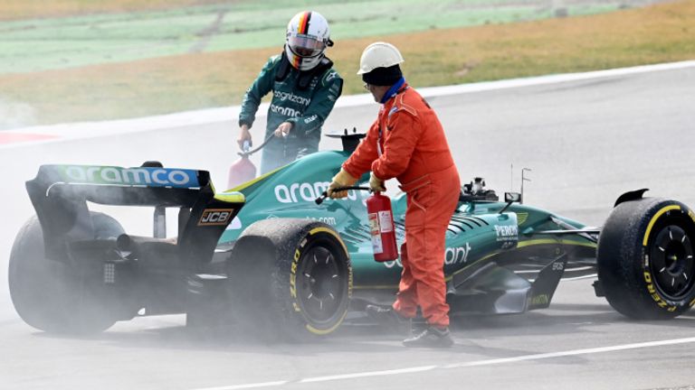 Les maréchaux assistent Sebastian Vettel après une fuite d'huile sur son Aston Martin