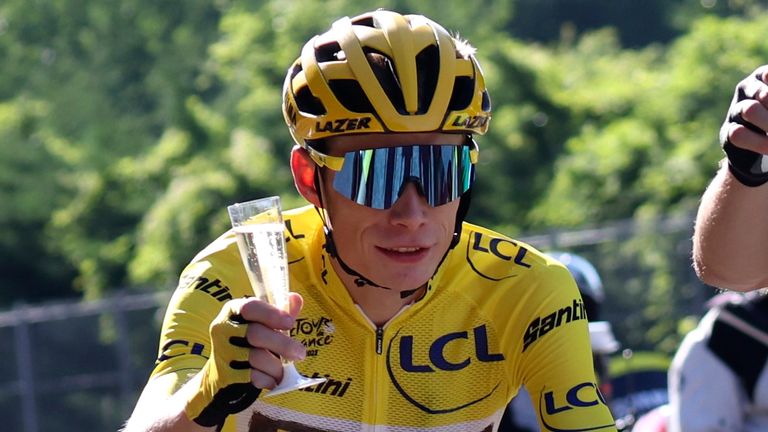 Denmark's Jonas Vingegaard, wearing the overall leader's yellow jersey, drinks champagne at the car of his team director during Stage 21