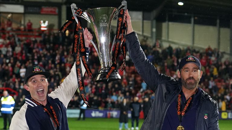 Wrexham co-owners Rob McElhenney and Ryan Reynolds celebrate with the National League trophy after promotion to 4th place