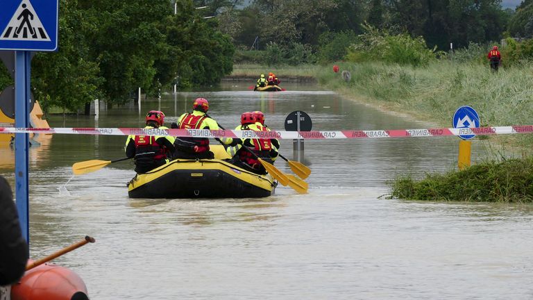 Firefighters use dinghies to cross a flooded road near Faenza in the Emilia Romagna region of Italy