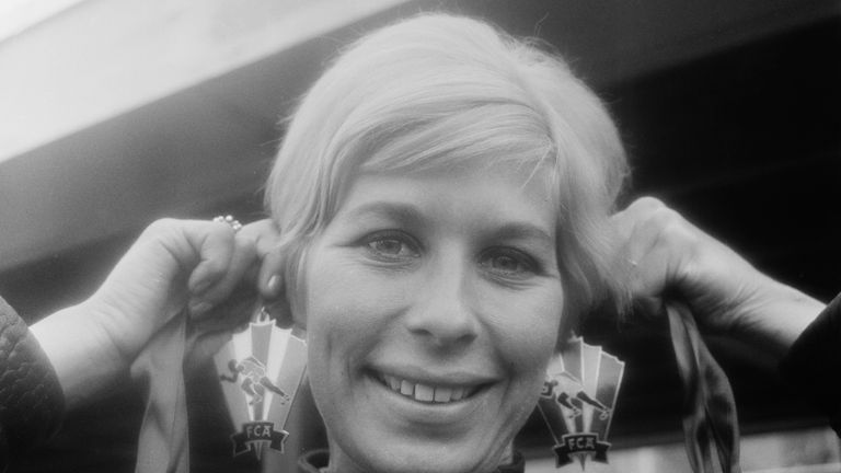 Rand tries on a pair of FCA (Cuban Athletics Federation) earrings in 1965