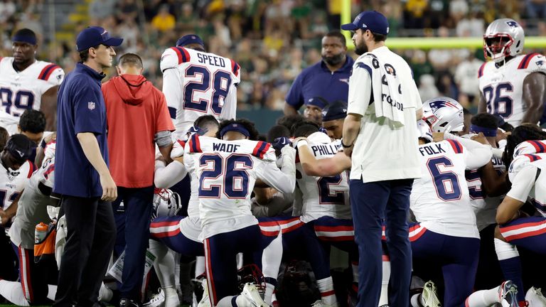 New England Patriots players kneel after cornerback Isaiah Bolden is stretchered off